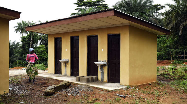 2019-ebola-praevention-sierra-leone-toiletten_C_Kai-Loeffelbein-16-9.jpg Eine Frau geht an Toilettenhäuschen und Waschbecken vorbei