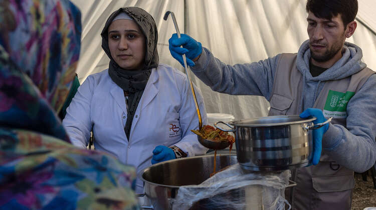 Nach Erdbeben in Türkei und Syrien: Verteilung von Mahlzeiten an Erdbebenopfer Eine Frau und ein Mann stehen in einem Zelt und verteilen Mahlzeiten.