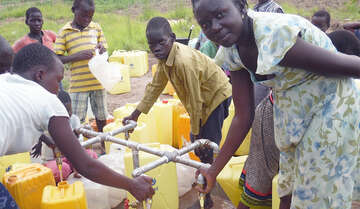 Flüchtlinge zapfen sich Wasser in ihre Kanister.