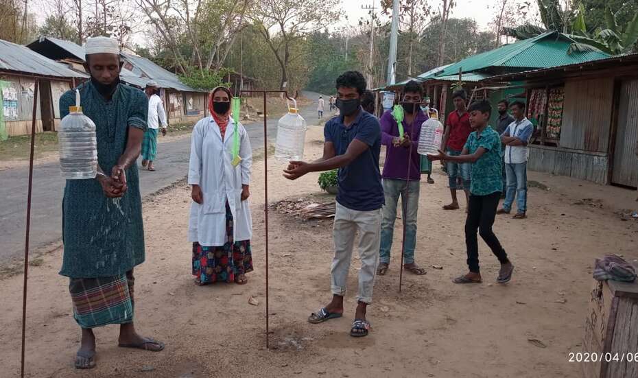Verschiedene Menschen waschen sich an Hygienestationen die Hände.
