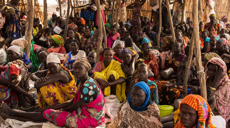 Frauen sitzen unter einem Bambusdach.