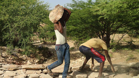 Männer tragen Steine und bauen einen Damm