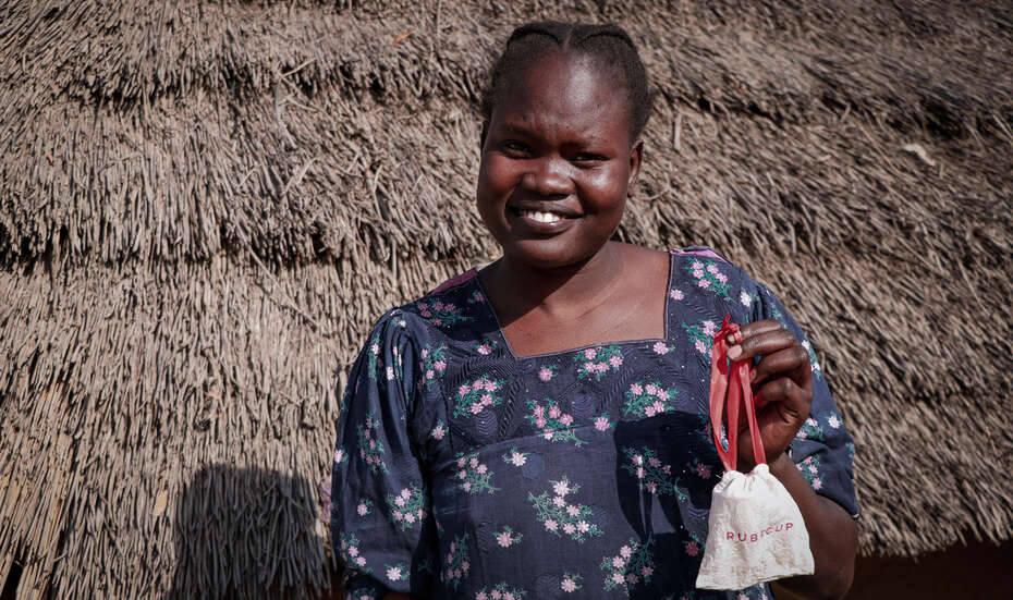 Eine junge Frau hält ein Säckchen mit einer Menstruationstasse in der Hand, Südsudan 2022. 