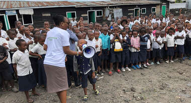 Ein Schüler sagt etwas durch ein Megafon, im Hintergrund viele weitere Schüler.
