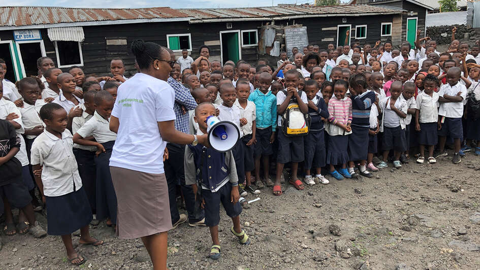 Ein Schüler sagt etwas durch ein Megafon, im Hintergrund viele weitere Schüler.