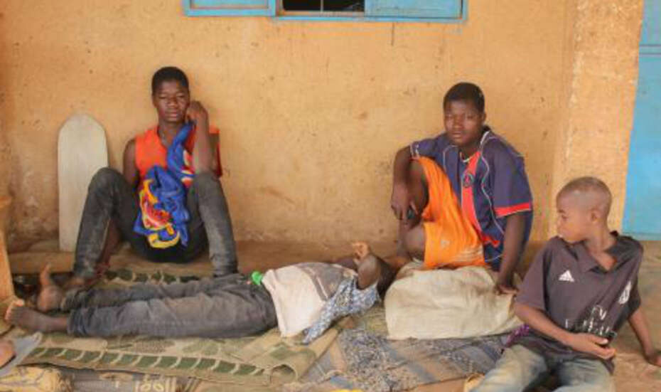 Jugendliche sitzen vor einem Haus, Burkina Faso.