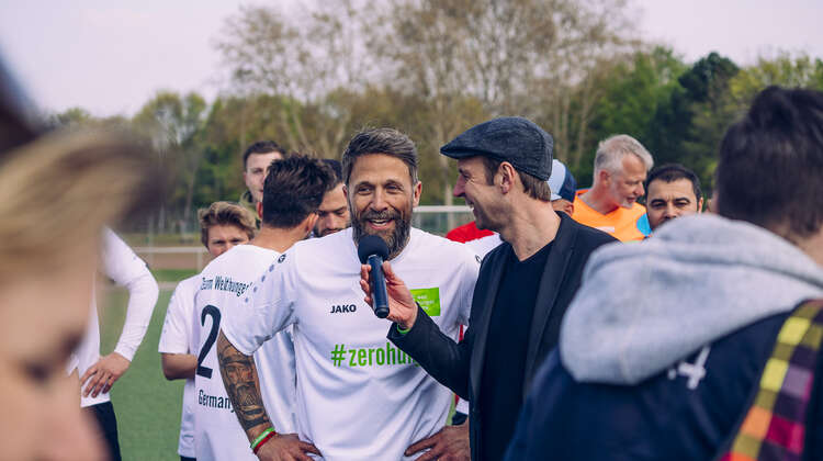 Florian Ambrosius in einem Fußballtrikot mit Aufschrift #zerohunger. Er wird interviewt.