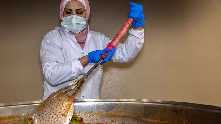 Eine Frau in einer Suppenküche rührt in einem großen Topf