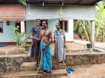 Familie vor ihrem Haus am Meer