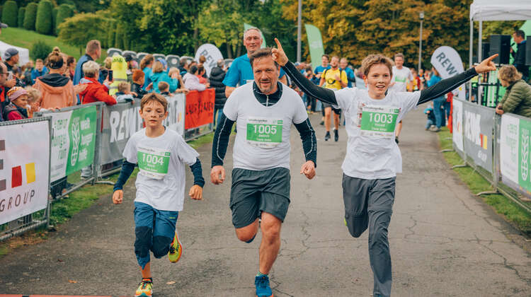 Zwei Kinder und ein Erwachsener laufen beim ZeroHungerRun ins Ziel