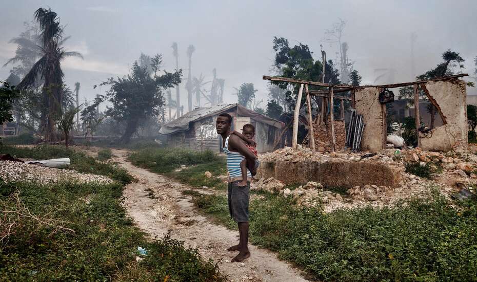 Ein Mann mit seiner Tochter vor den Ruinen eines Hauses in Grand Anse.