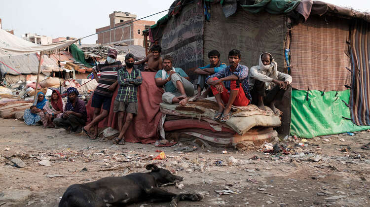 2020-coronavirus-obdachlosenunterkunft-vortrag-delhi-indien-c-florian-lang.jpg Mehrere Männer sitzen auf einem Stapel Matratzen.