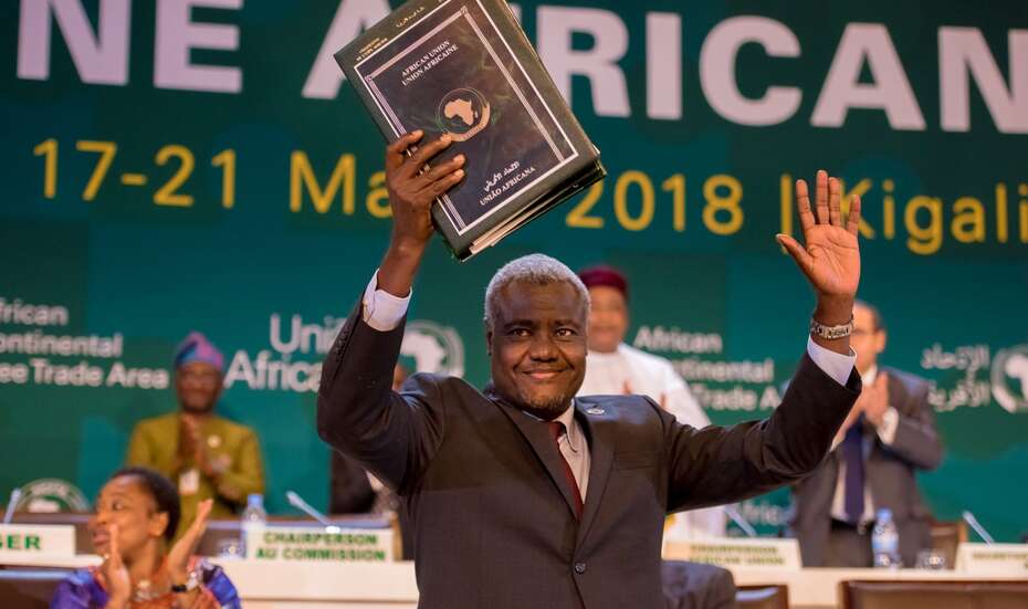 AfCFTA_AU_Commission_Chair_2018.jpg Moussa Faki Mahamat hält eine Mappe hoch und feiert die Unterzeichnung des Freihandelsabkommens durch die Staats- und Regierungschefs, Kigali, 2018.