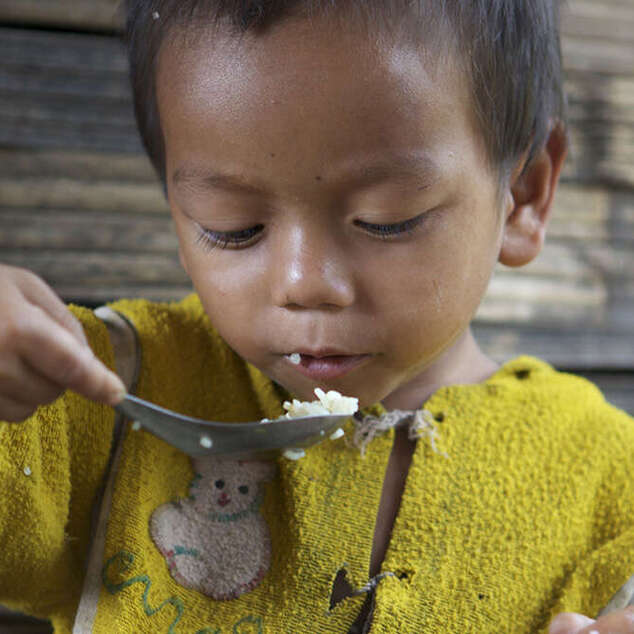 Ein kleiner Junge isst Reis aus dem Topf