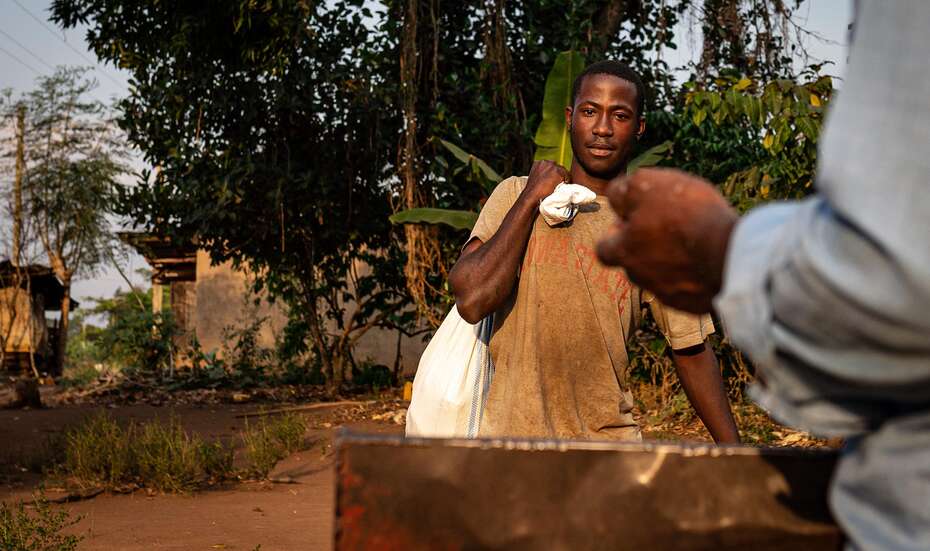 Ein Bauer aus Uganda bring seine Maisernte zum Schälen, 2021. 