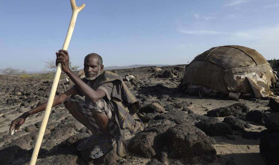 Ein Äthiopier hockt vor seinem Zelt inmitten einer kargen Umgebung
