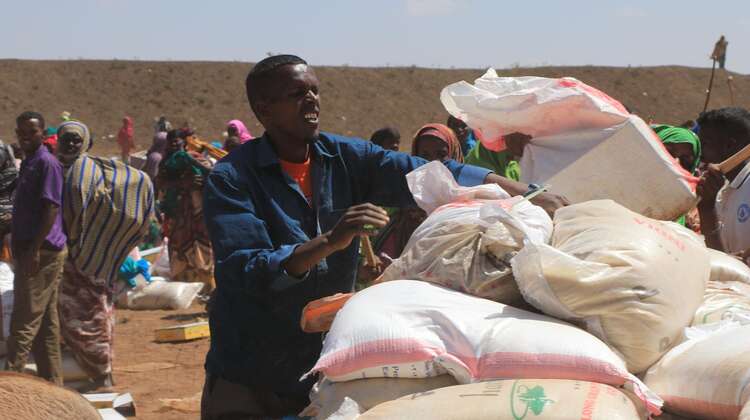 Ein Mann verteilt Hilfspakete an umstehende Menschen