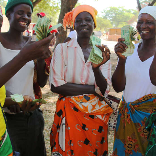 Fünf Frauen halten Geld in die Kamera, das sie als Kredit für ihre Unternehmensgründung erhalten haben.