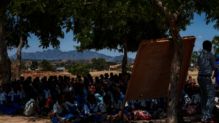 Kinder sitzen auf dem Boden und hören zu.