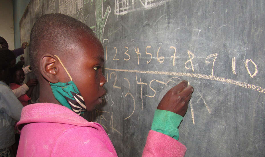 Ein Mädchen steht an der Tafel und rechnet, Malawi 2021. 