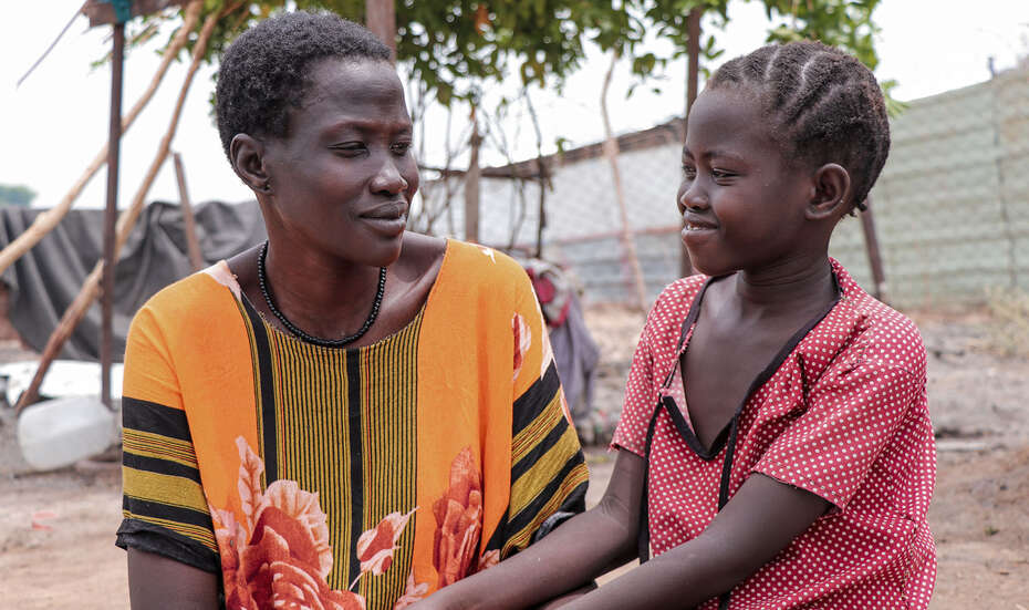 Eine Frau und ihre Tochter schauen sich in die Augen und lächeln