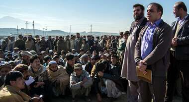 Flüchtlinge in Winterkleidung warten auf die Verteilung von Haushaltsgütern