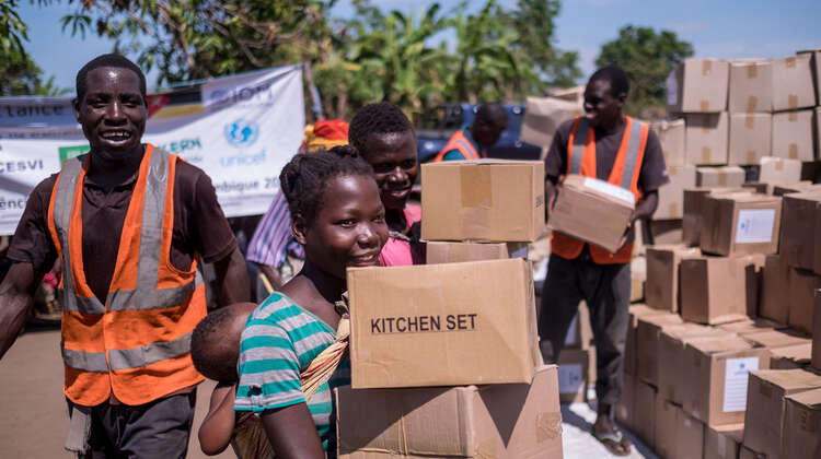 2019-nothilfe-nhamatanda-verteilung-hilfsgueter-mosambik-tommy-trenchard-concern-2.jpg Eine Frau läuft von einer Hilfsgüter-Verteilung weg. In ihren Händen hält sie Kartons.