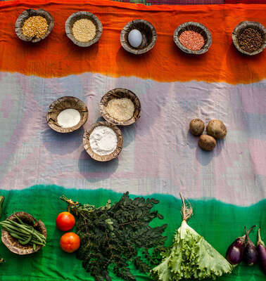 Auf dem Boden liegt eine indische Flagge, darauf stehen verschiedene Lebensmittel.
