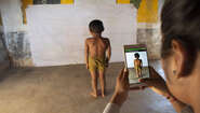 2020-indien-child-growth-monitor-smartphone-kind.jpg Eine Frau verwendet das Smartphone mit der Child Growth Monitor App um die Entwicklung eines Kindes zu messen, Indien 2020.