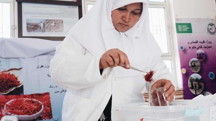 2021-safran-frauen-afghanistan-c-IlirTsouko.jpg Eine Frau hält eine Pinzette mit Safran. In der anderen Hand hält sie ein Glas.