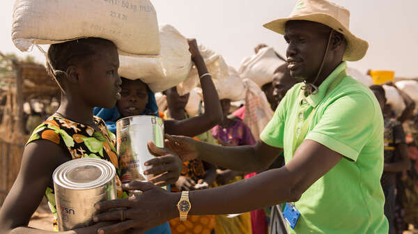 Ein Mitarbeiter der Welthungerhilfe reicht einer Frau im Flüchtlingscamp Bentiu Hilfsgüter