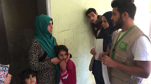 Eine Flüchtlingsfamilie n der Türkei spricht mit einem Mitarbeiter der Welthungerhilfe