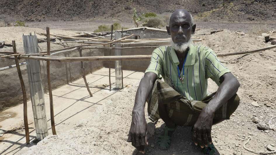 Yusuf sitzt auf dem ausgetrockneten Boden in seinem Dorf Afar © Jens Grossmann