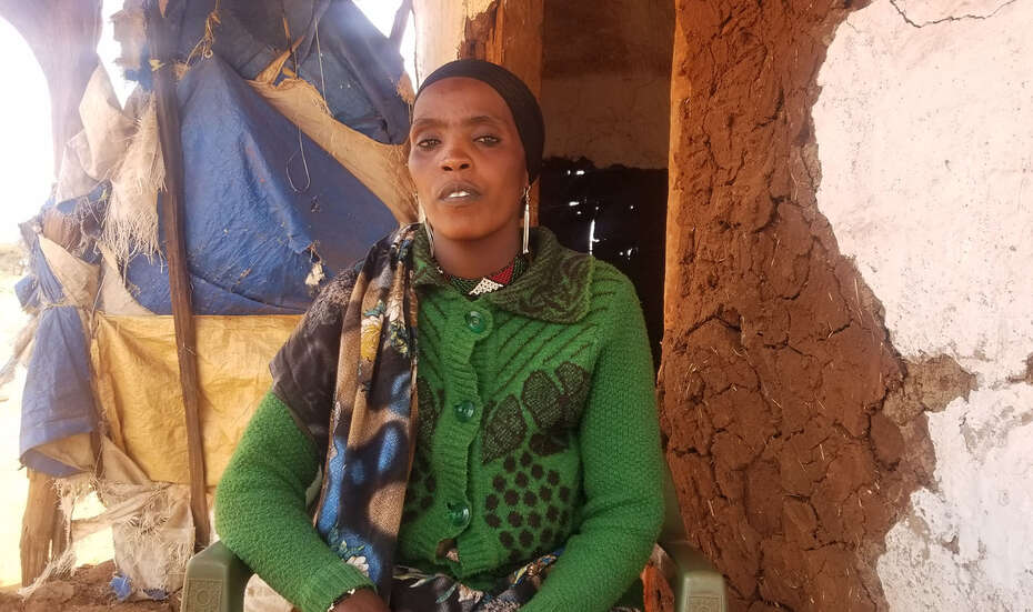 Eine Frau aus Äthiopien sitzt vor ihrem Haus und schaut in die Kamera.
