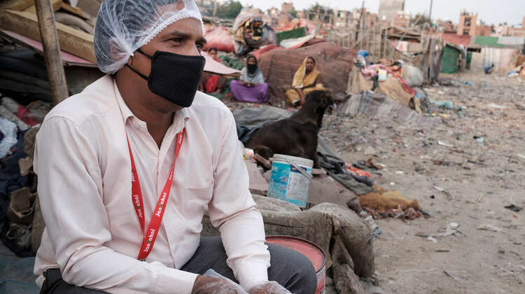 2020-coronacirus-obdachlosenunterkunft-sozialarbeiter-delhi-indien-c-florian-lang.jpg Ein Mann in weißer Kleidung, mit Handschuhen, Mundschutz und einer Plastikhaube auf dem Kopf