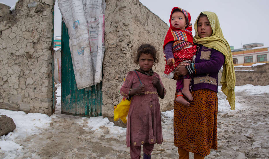 Eine Frau mit ihren beiden Kindern in einem Camp im Winter – eine Vielzahl an Fluchtursachen in Afghanistan hat sie dazu bewegt, ihr Land zu verlassen.