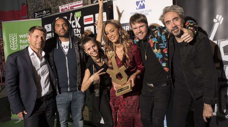 Rock gegen Hunger 2019: Gruppenfoto mit dem Logo des Marketing Clubs Köln-Bonn im Hintergrund.