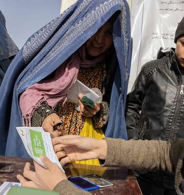 Eine Frau lächelt und nimmt ein Registrierungsausweis entgegen.