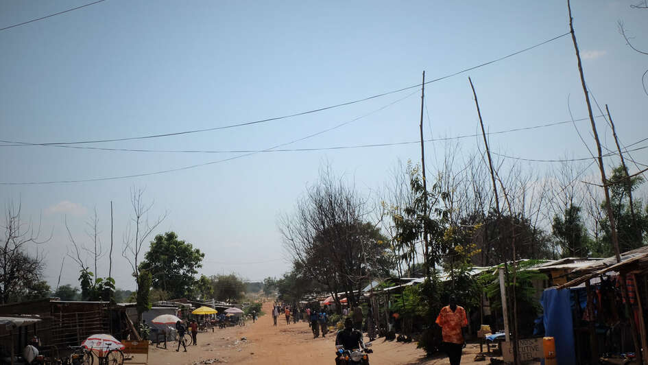 Menschen laufen eine sandige, trockene Straße entlang.