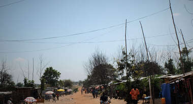 Menschen laufen eine sandige, trockene Straße entlang.