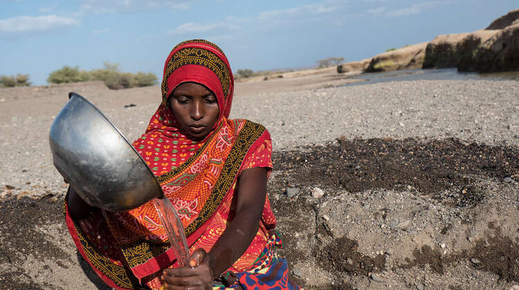 Eine Frau schüttet Wasser in einen Kanister.