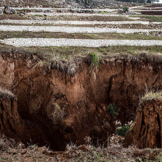 Ein kraterartiges Loch in der Erde. Im Hintergrund sieht man weiße Schutzwälle.