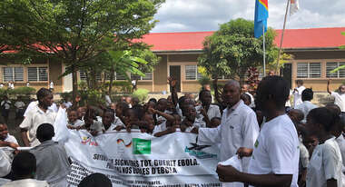 Menschen halten ein Plakat zur Prävention von Ebola in die Höhe.