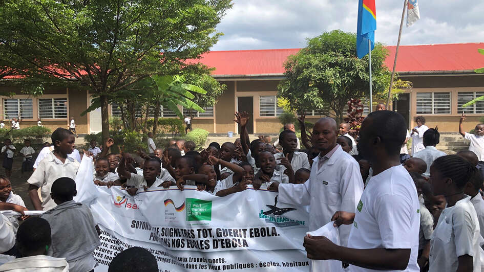 Menschen halten ein Plakat zur Prävention von Ebola in die Höhe.