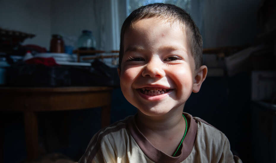 Kleiner Junge lächelt für Portraitfoto in die Kamera.