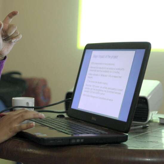 Detailaufnahme von einer Person, die etwas an einem Computer zeigt.