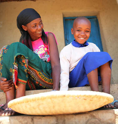 Eine Frau und ein Mädchen sitzen auf einer Treppe, vor ihnen ein flacher Korb.