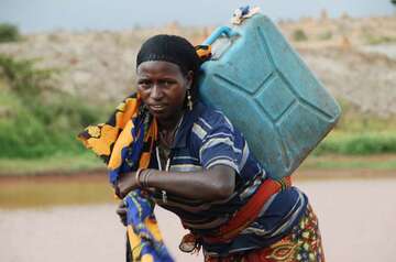 Eine Frau schleppt einen Wasserkanister.