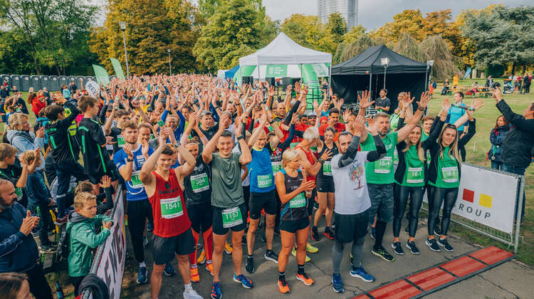 Eine große Menge an Läufer*innen steht an der Startlinie eines Spendenlaufs und hält die Hände in die Höhe.