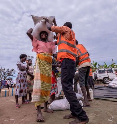 Eine Frau bekommt von einem Mann in Sicherheitsweste Säcke und Pakete.